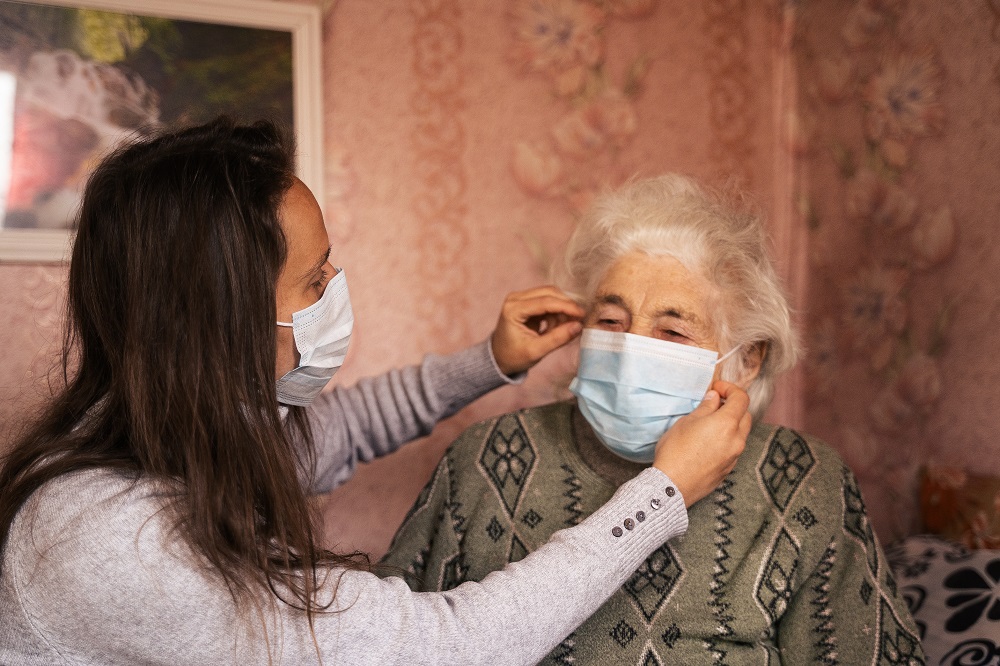 Lady fitting elderly lady with face mask